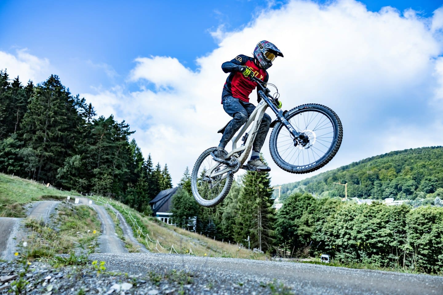 Ein Mountainbiker springt mit seinem Rad über einen Feldweg.