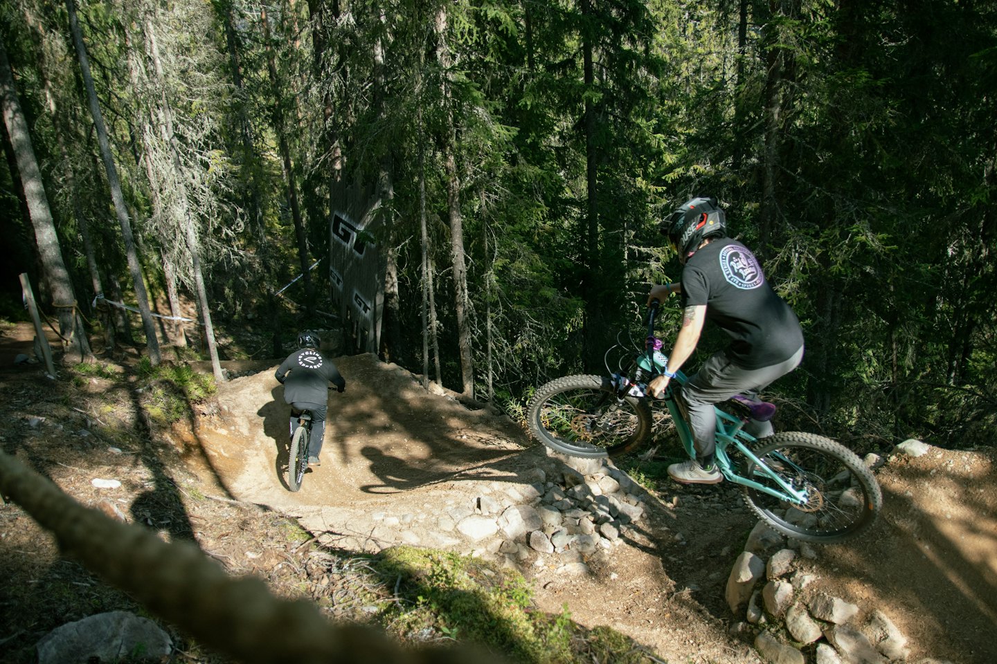 Zwei Mountainbiker fahren einen gewundenen Waldweg hinunter.