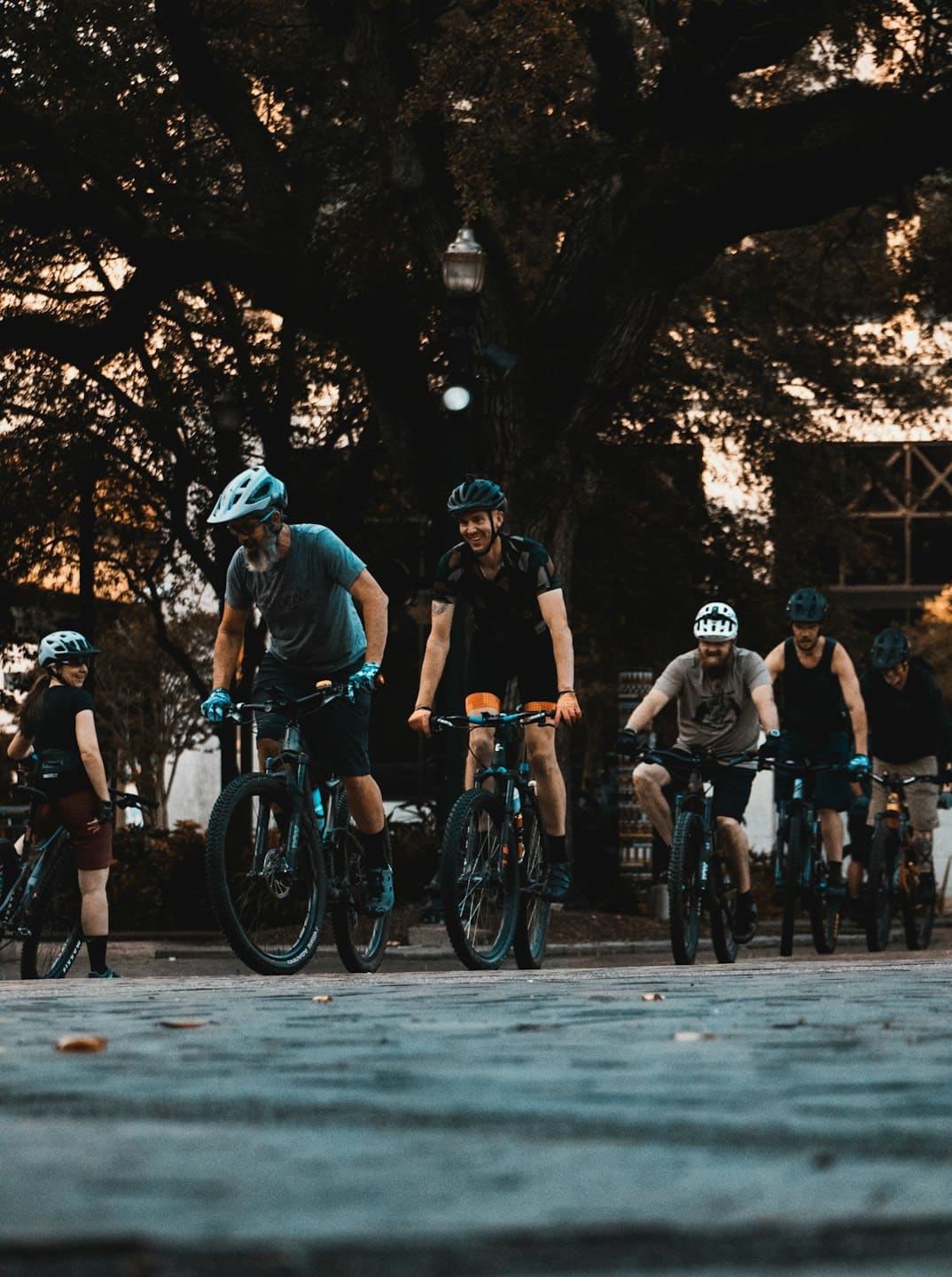 Sechs Radfahrer versammeln sich mit ihren Fahrrädern in einem Park.