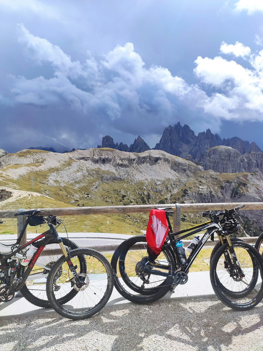 Zwei Mountainbikes, die an einem rustikalen Zaun mit Blick auf felsige Berge geparkt sind.