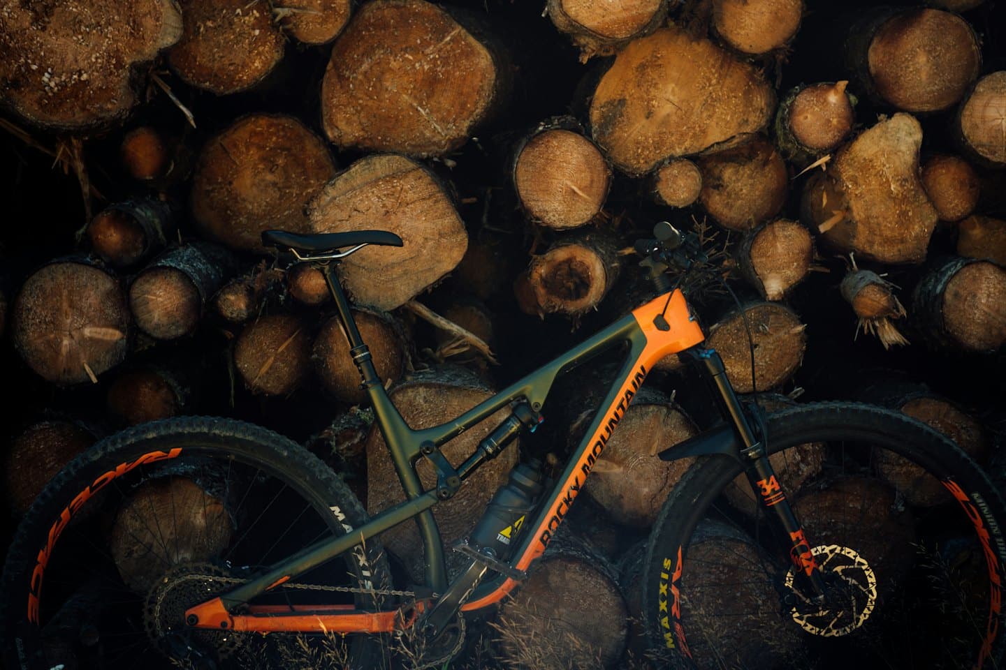 Ein Mountainbike lehnt an einer Wand aus Holzstämmen.
